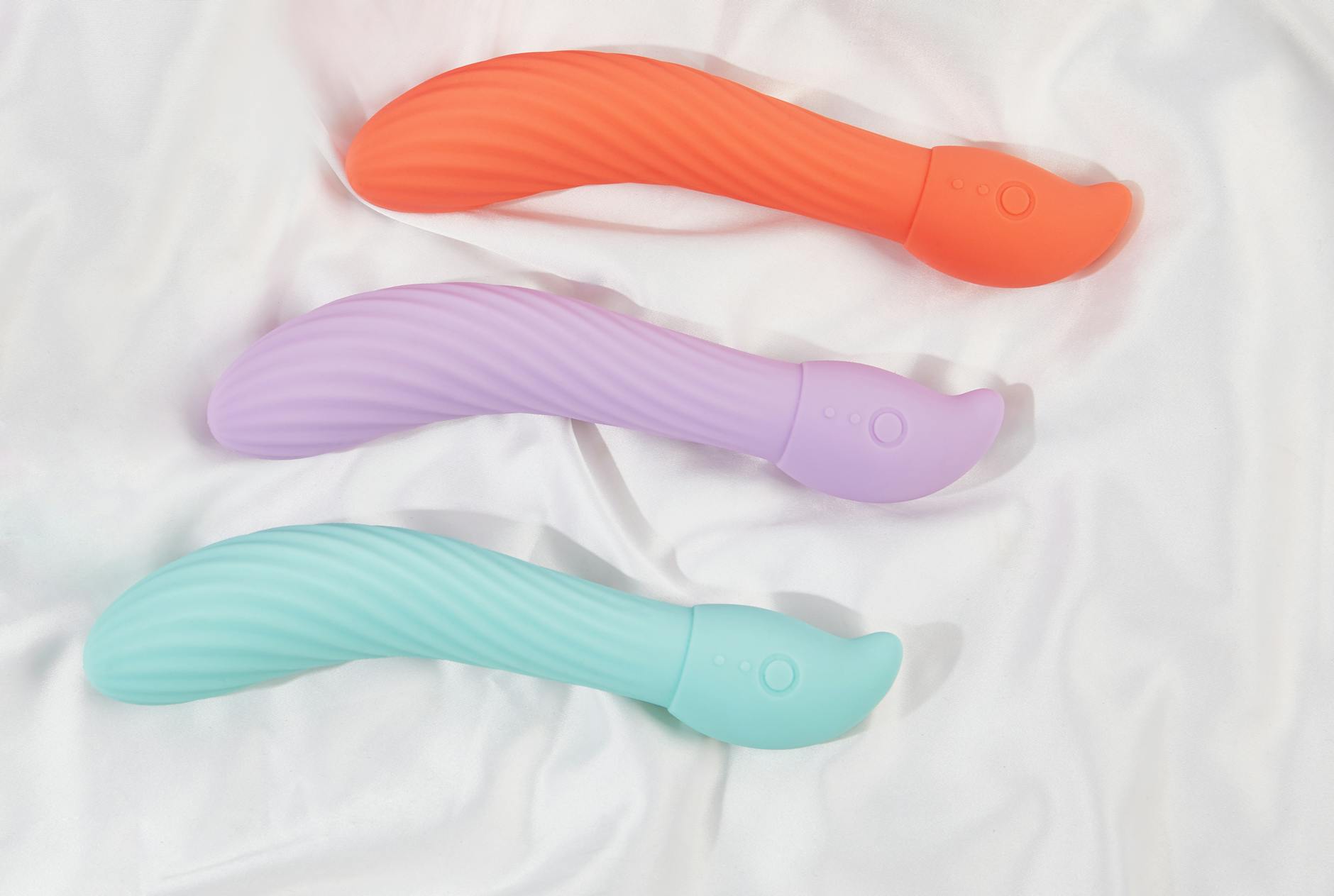 A hand holding an orange vibrator against a minimalistic purple backdrop, showcasing modern sensuality.
