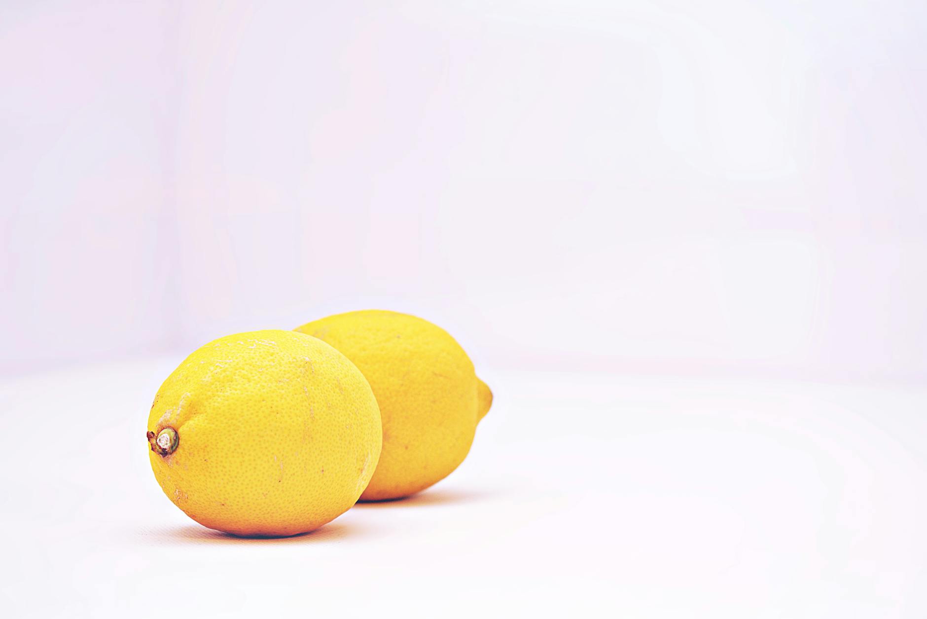 Two vibrant lemons on a minimalist white background, representing fresh, focused external pleasure