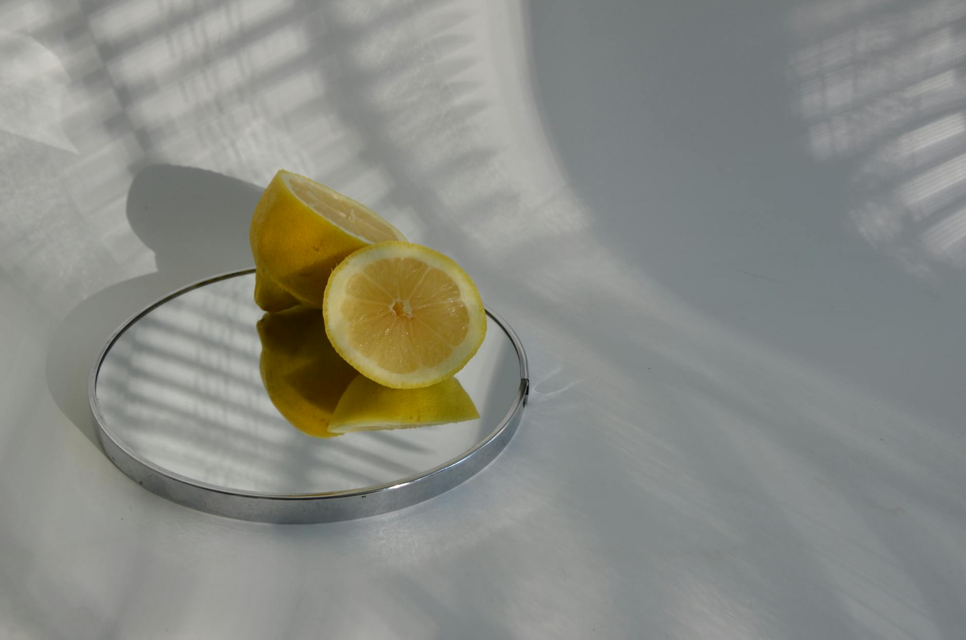 Sliced lemons on a mirror casting soft shadows, symbolizing fresh approaches to pleasure.
