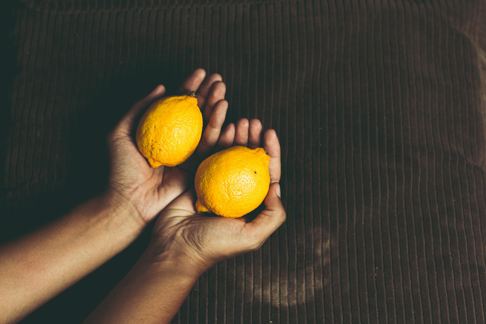Two fresh lemons held in cupped hands, symbolizing renewal and fresh starts.