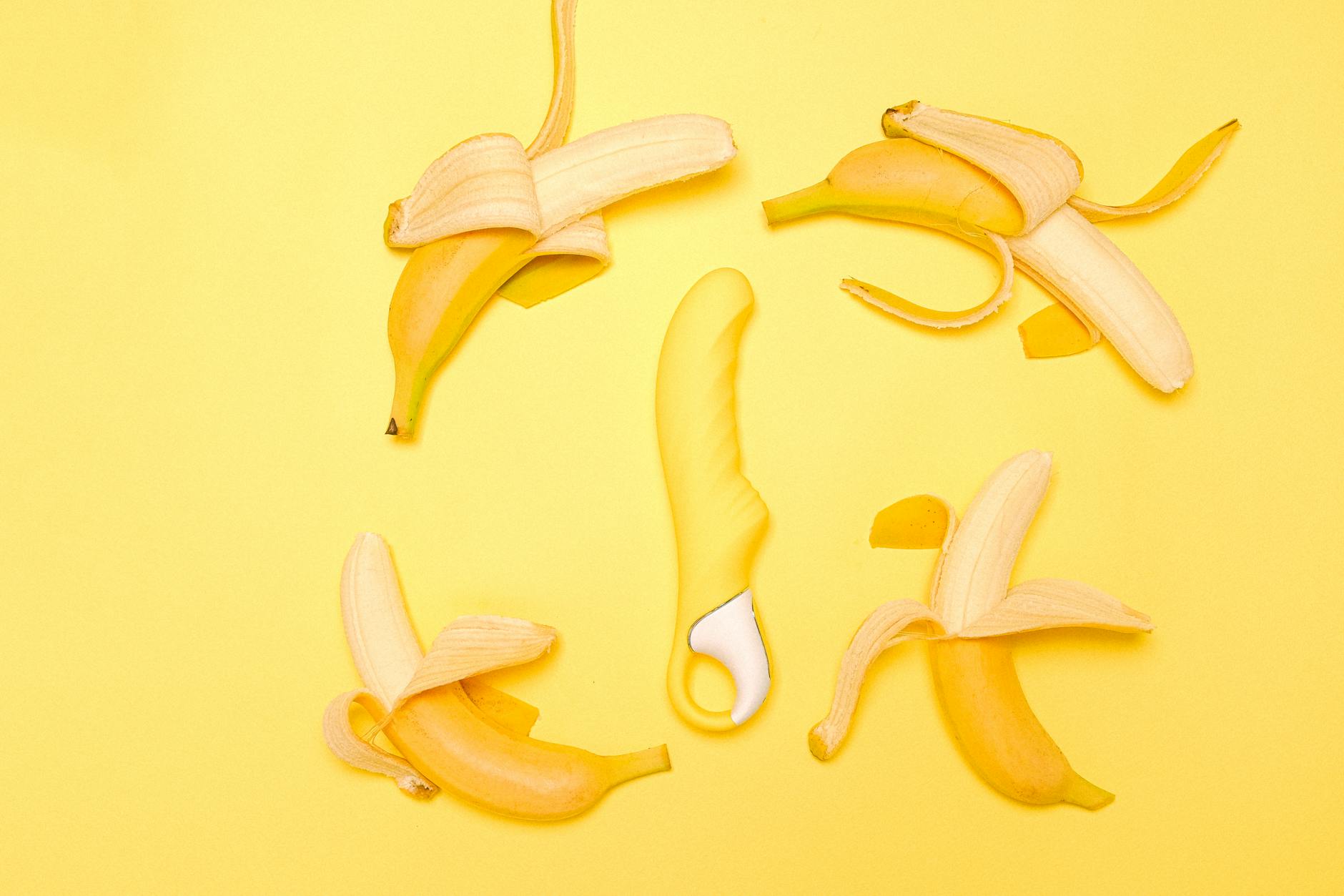 Yellow silicone lemon vibrator on a bright yellow background with fresh lemons