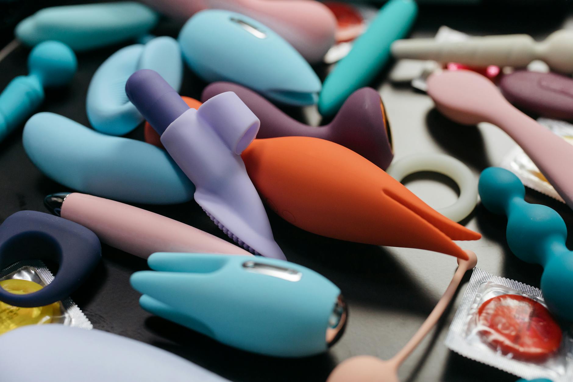 A collection of colorful clitoral vibrators including a yellow lemon vibrator displayed among other toys