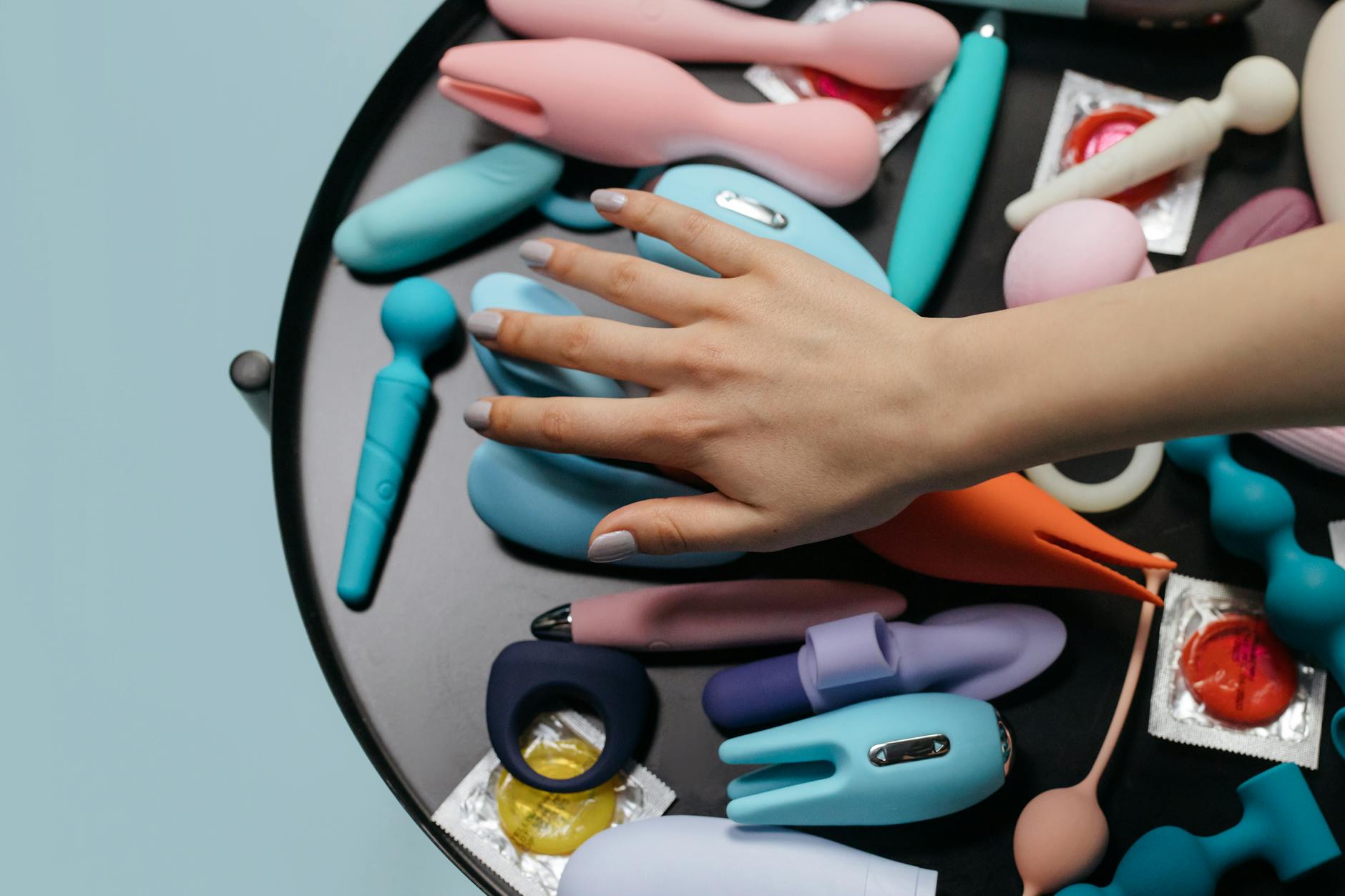 A selection of colorful clitoral vibrators and adult toys arranged together on a neutral surface.