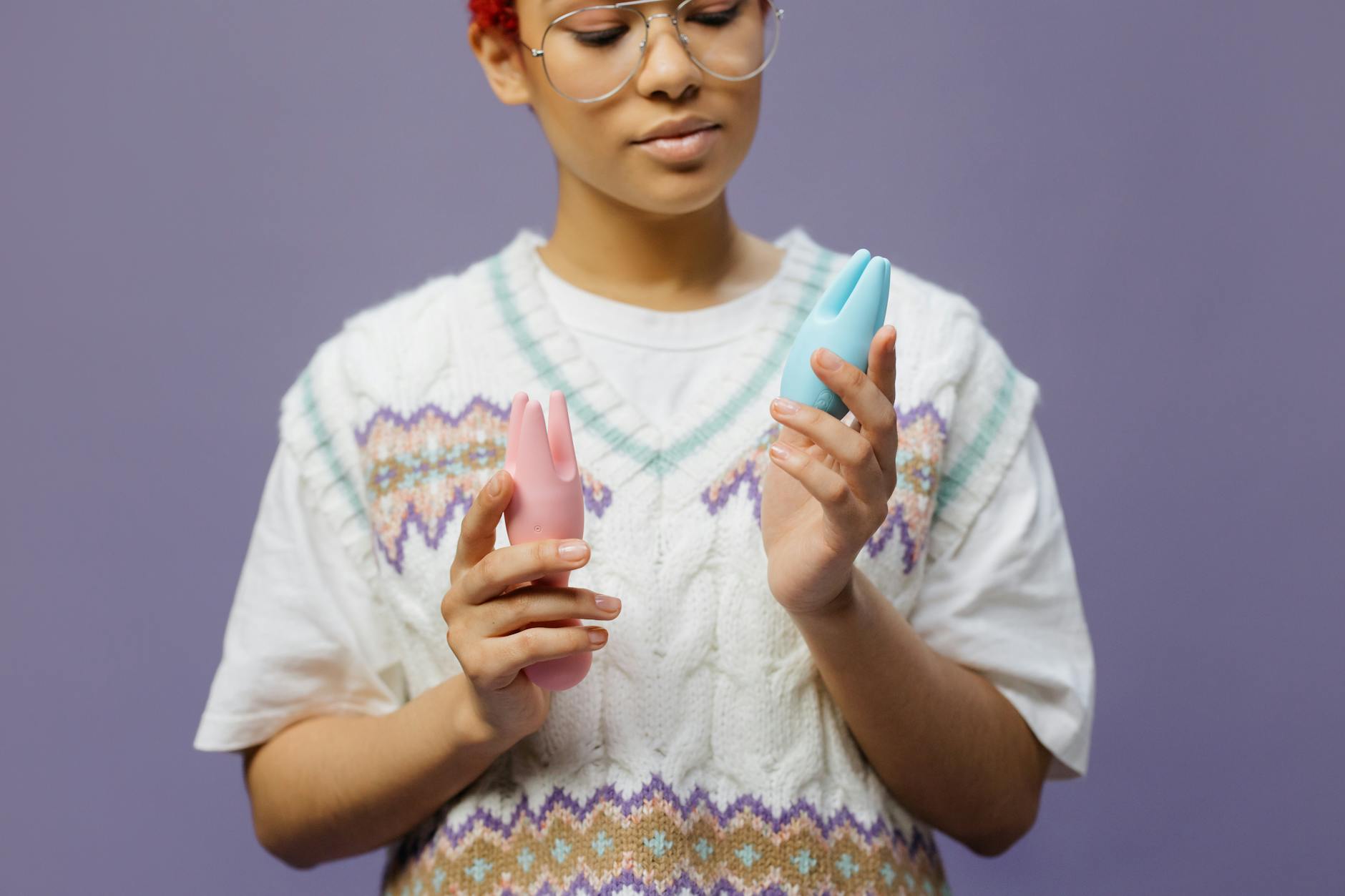 Woman holding colorful vibrators in thoughtful pose