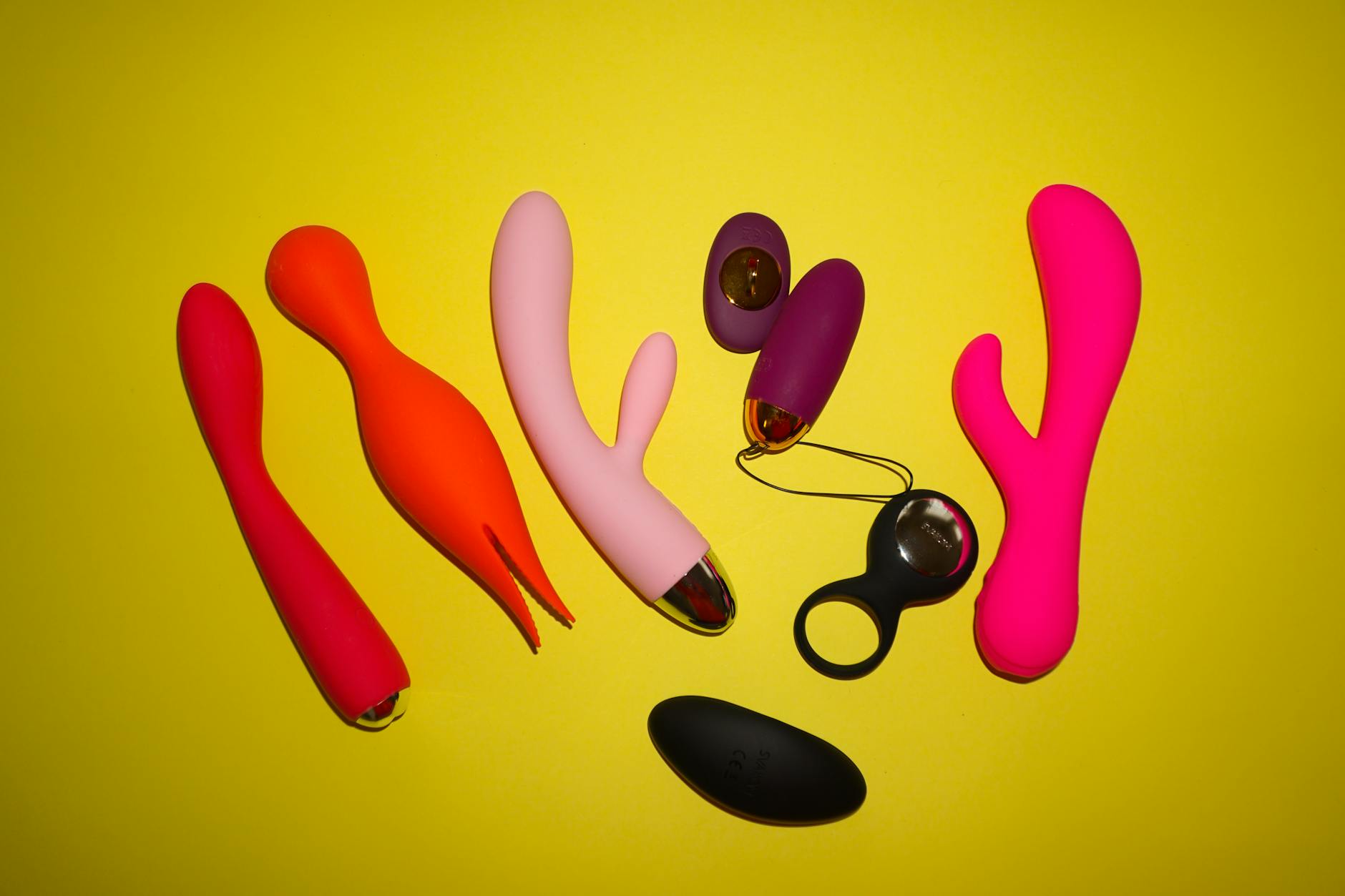 Colorful clitoral vibrators arranged on a bright yellow background
