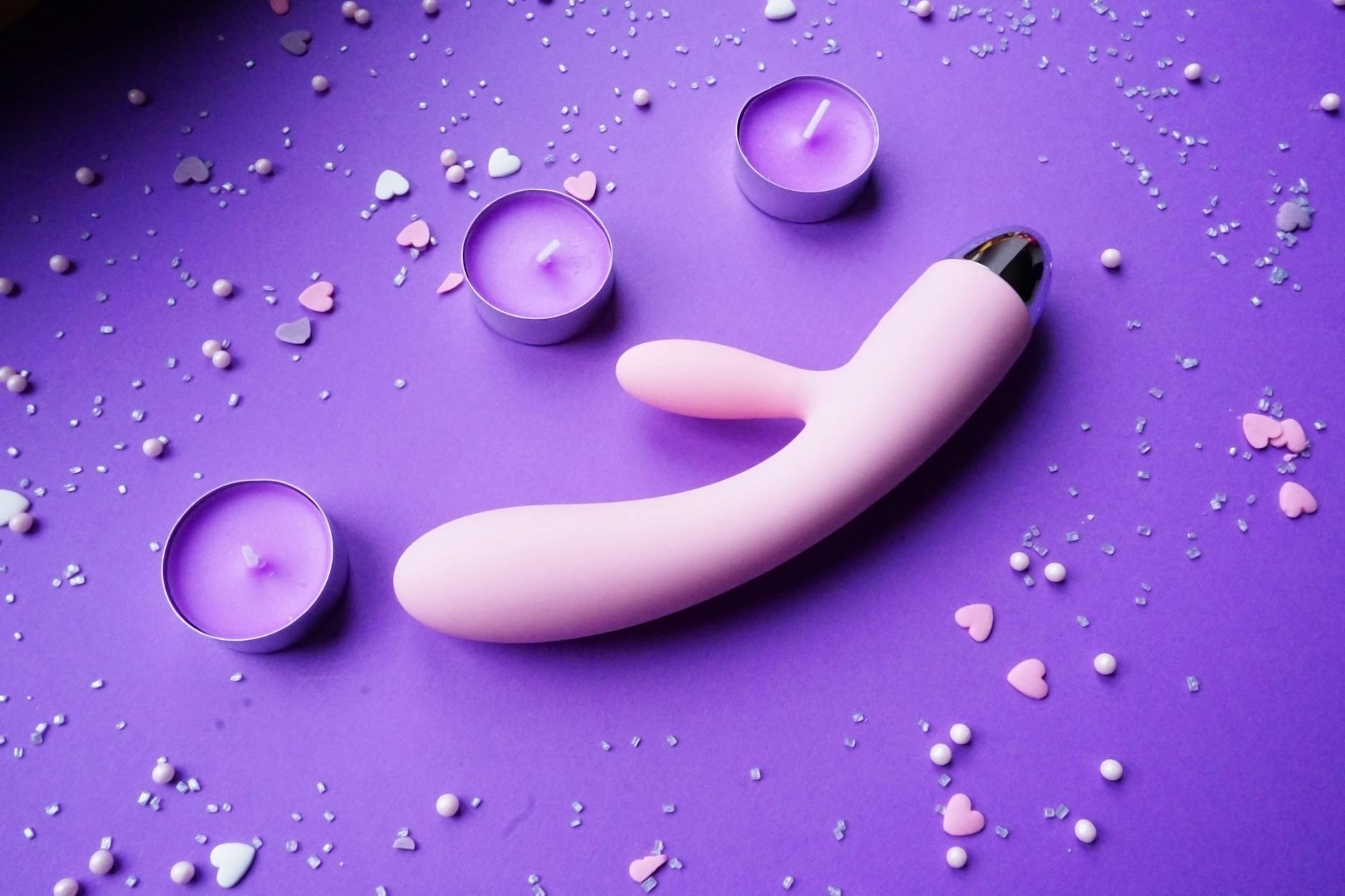 Vibrator displayed with candles and heart confetti in a calm, intimate setting
